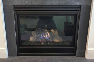 Black glass-front fireplace insert with visible logs
