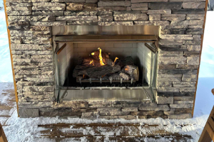 Rustic stone fireplace with wood mantel and fire burning