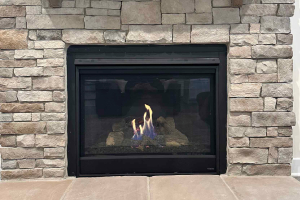 Small built-in fireplace with visible flame in stone wall