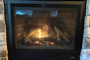Close-up view of fireplace logs with flame inside firebox
