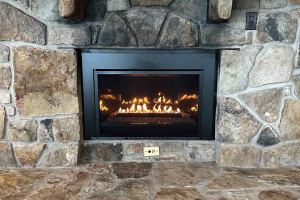 Stone fireplace with black insert and visible flames